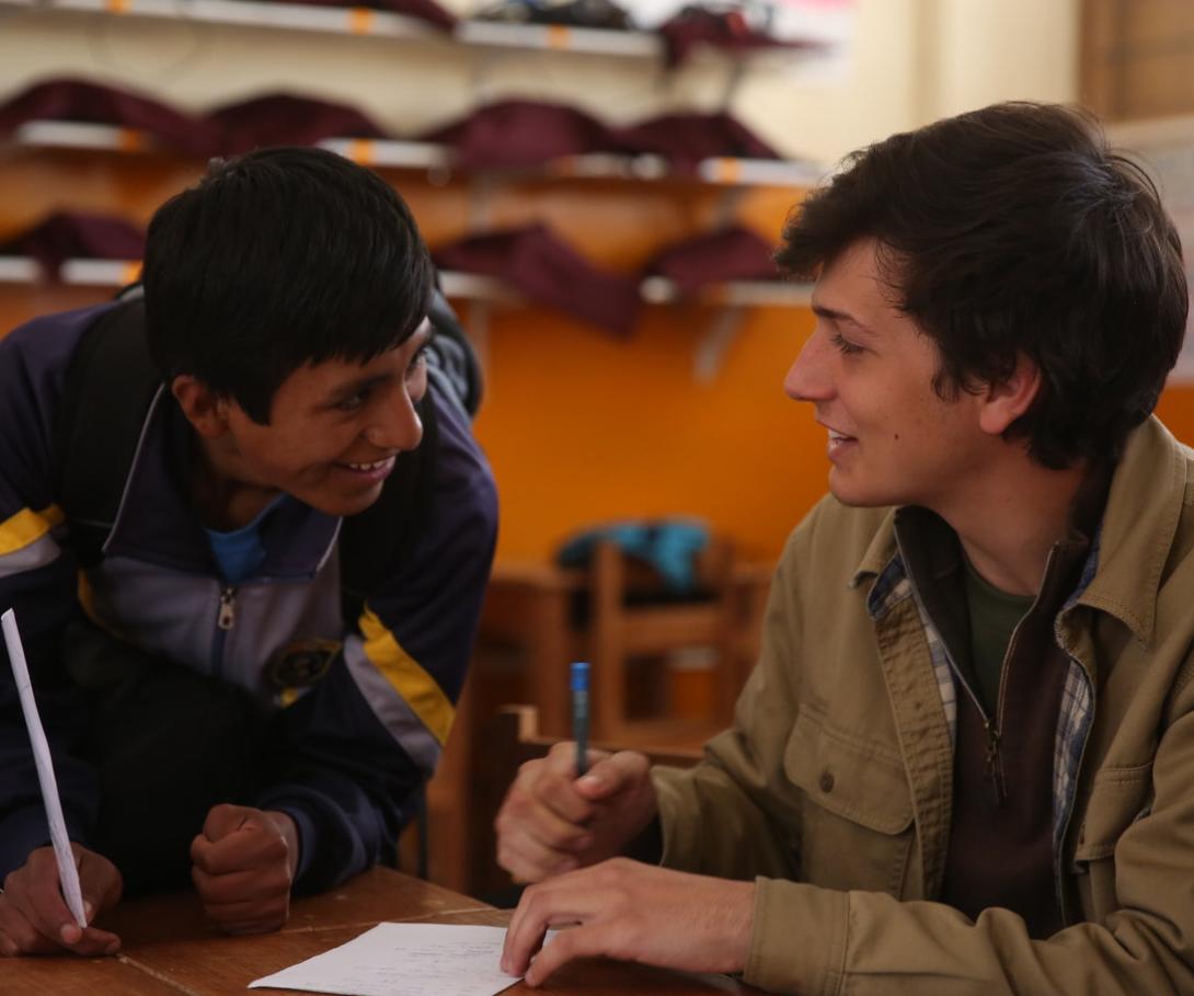 A student pratices his English with a volunteer teacher at a school in Peru. A volunteer teaching English in Peru chats to a student between classes.